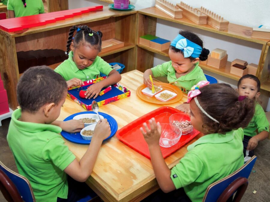 Niños y niñas trabajan con bandejas de material Montessori en el aula