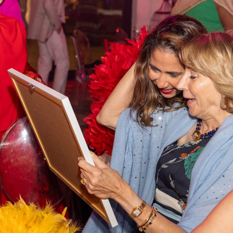 Invitadas contemplan una obra de arte en la gala Adopte Una Cuna
