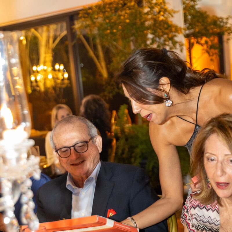 Invitados hojean el libro conmemorativo en la gala Adopte Una Cuna 2026