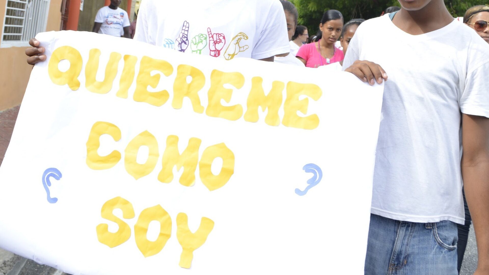 Cartel pintado a mano que dice «Quiéreme como soy», con el símbolo de la sordera, en la marcha por la inclusión del Hogar del Niño