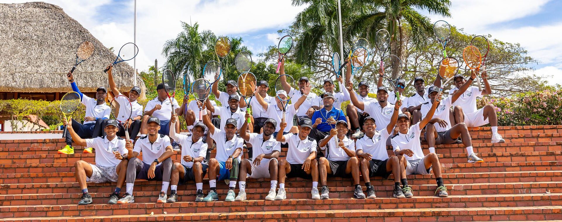 Participantes del Torneo de Tenis McDaniel, sentados en las gradas con las raquetas en alto