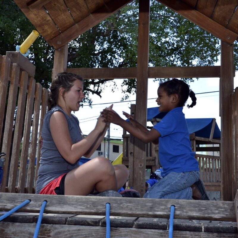 Voluntaria jugando con una niña en el parque infantil
