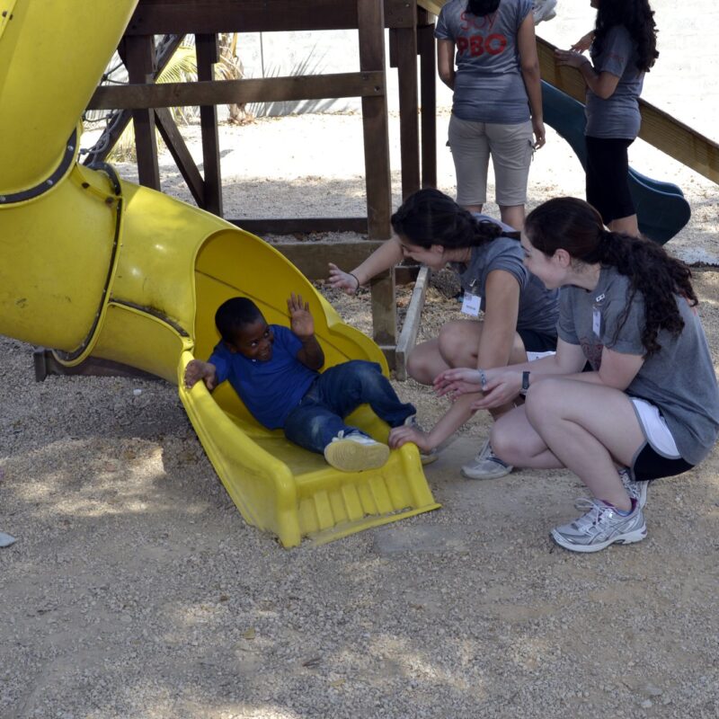 Voluntarias con los niños en el tobogán del Hogar del Niño